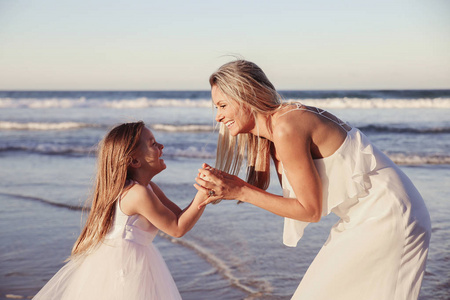美丽的母亲和女儿一起欢笑在海滩上