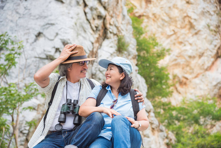退休的亚洲情侣坐在山上, 一起微笑
