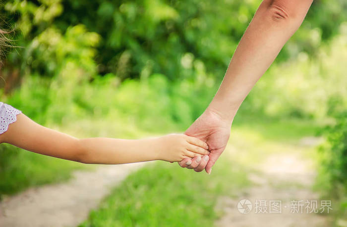 妈妈和女儿牵着手走在路上.选择性对焦.自然