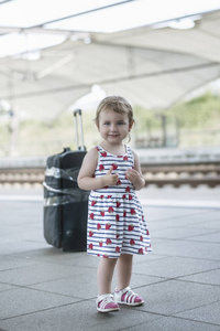 小可爱的女孩与一个大手提箱在一个废弃的铁路平台上