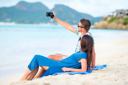 快乐情侣在蜜月度假的白色沙滩上拍照