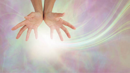 散发柔和的疗愈能量女性手对粉彩色的空灵背景与白色能量球和拷贝空间