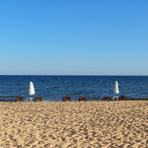 海滩与日光浴在风景如画的蓝色海海湾的背景下。晚间时间