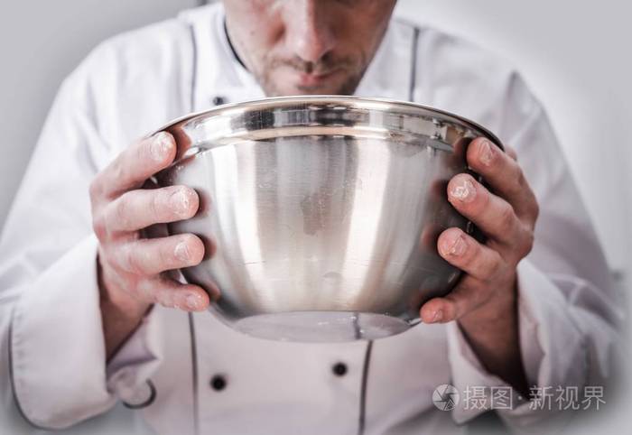 厨厨烹调时间白种厨师在食物准备过程中手里拿着不锈钢碗