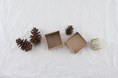棕色礼品盒饰以松果和绳子在薄纱织物背景