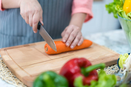 手拿刀切胡萝卜。女人在餐桌上准备食物。厨师烹调美味的晚餐。需要技能的工作