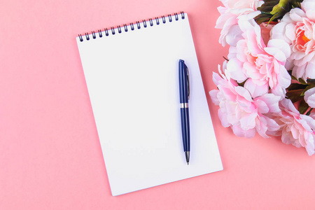 带蓝色钢笔的空白笔记本, 上面有粉红色的粉彩背景。模型, 框架, 模板