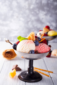 三个美味的柠檬香草和草莓味的冷冻甜点在一个碗里与硅片秸秆和冰莓的木质背景