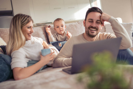 快乐的家庭在家享受和看卡通片在笔记本电脑上