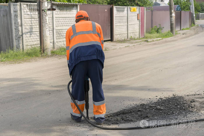 道路维修工人正在修路这个人正在用手提钻