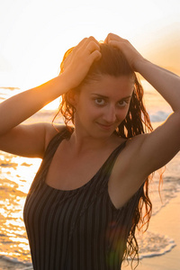 关闭海滩上有魅力的年轻女子的肖像。在背景海和日落。垂直框式射击