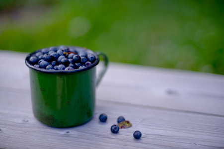 蓝莓在木桌上的绿杯子里