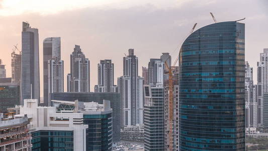 迪拜商业海湾塔在日落空中 timelapse。一些摩天大楼和在建的新塔楼的屋顶视图