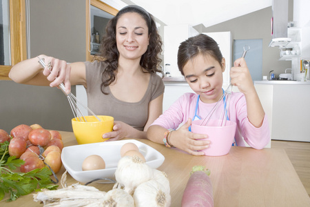 妈妈和年轻的女儿打鸡蛋在一个家庭的厨房