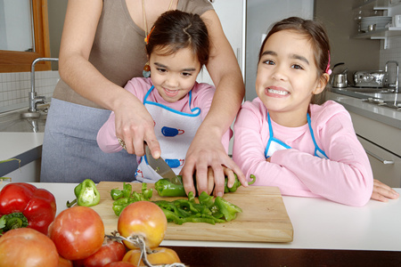 母亲和双女儿学习来一起在厨房里切菜