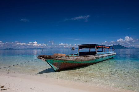 孤独的木制船停泊在水晶般清澈的热带小岛上