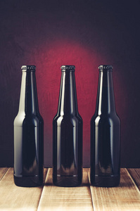 黑瓶啤酒的红色背景上的木制货架黑瓶啤酒的红色背景的木架子。色调和选择性焦点