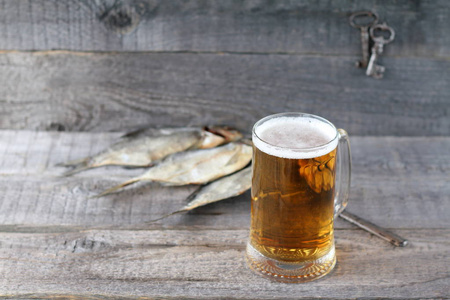 一杯淡啤酒和干鱼在木质背景下