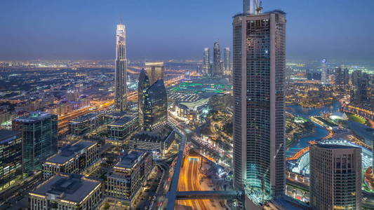 迪拜市中心天到夜转折 timelapse 现代塔全景从顶部在迪拜, 阿拉伯联合酋长国。交通在路和音乐喷泉