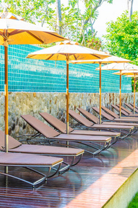 美丽的雨伞和椅子周围游泳池在酒店和度假概念