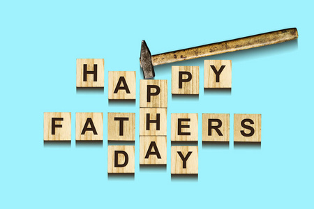 快乐的父亲节题字在木立方体与工作工具在蓝色背景, 隔绝。快乐的父亲日概念。问候和礼物