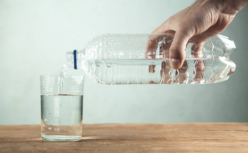 人手从瓶子里倒出干净的水变成玻璃
