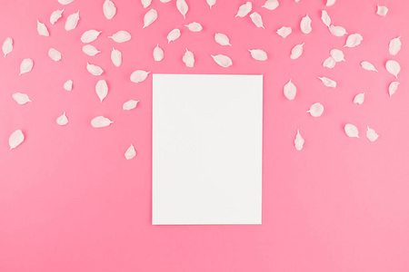 创意平躺概念空白明信片模型的顶部视图和苹果树花花瓣在柔和的粉红色背景与拷贝空间在极小的样式, 文本模板