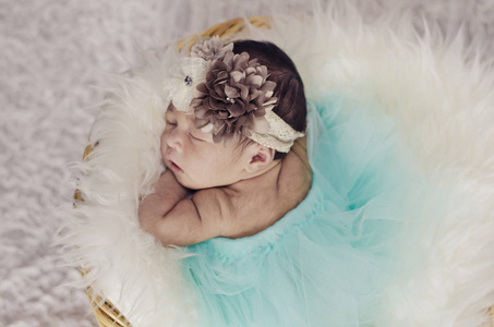 可爱的新生婴儿的肖像, 花头带睡在篮子覆盖着毛茸茸的垫子。新的生活和养育的概念. 从上角射出