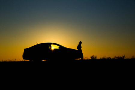 轿车与女孩的美丽的日落背景的剪影