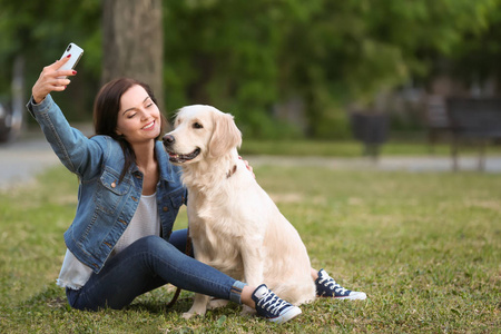 一个年轻的女人带着自拍和她的狗一起在公园里。宠物护理