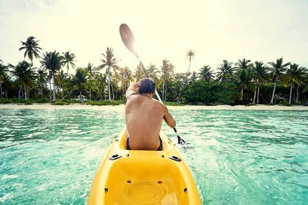 年轻人在热带平静的泻湖上划海皮艇