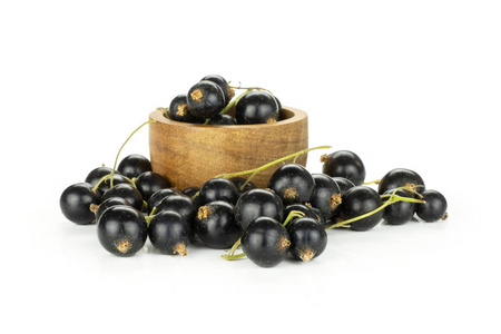 很多新鲜的黑醋栗浆果本盖恩品种在一个木碗与浆果栈前孤立的白色