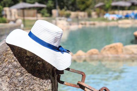 一个阳光明媚的日子, 在夏天的一个可爱的水池上倚着一顶孤白色的帽子