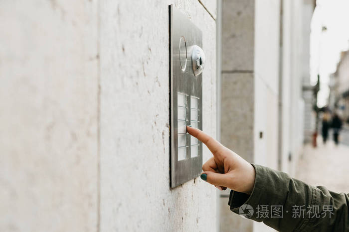 关闭女性手按门铃按钮.那个女孩在呼唤对讲机