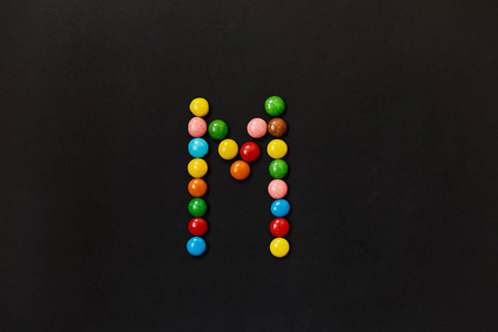 用彩色糖果做的英文字母表。字母 M