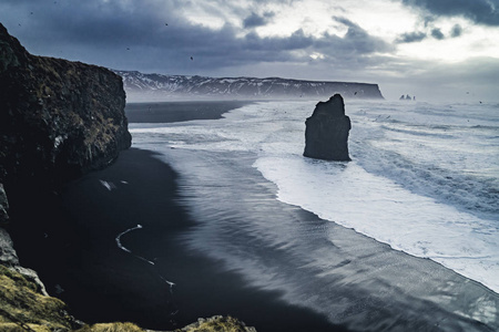 在冰岛著名的黑色沙滩 Reynisfjara 日出。刮风的早晨。海浪。五彩缤纷的天空。早晨日落