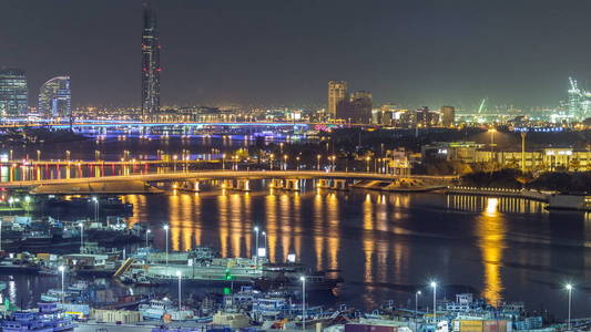 迪拜小河风景夜 timelapse 与小船和游艇和现代大厦与交通在桥梁。高空俯视图