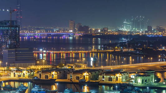 迪拜小河风景夜 timelapse 与小船和游艇在口岸和现代大厦与交通在桥梁。高空俯视图