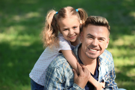 快乐的父亲和女儿在绿色公园