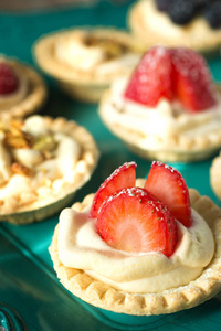 蓝莓, 草莓和开心果 tartlets 和勺子在一张木桌上