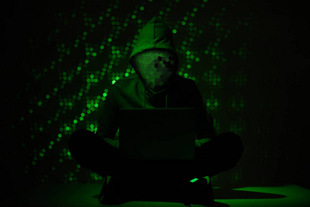 用膝上型电脑在帽衫中的黑客剪影色调图片