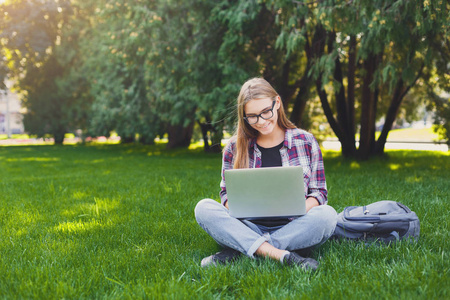 快乐的年轻妇女使用手提电脑在公园