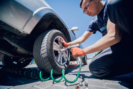 专业的汽车修理工在汽车维修服务的气动扳手工作。车轮修理