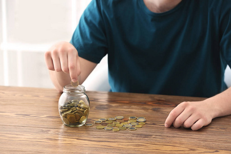 人们把硬币放在桌上的玻璃瓶里。储蓄概念