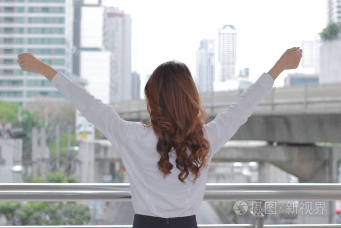 成功青年艾伦的背影在城市建筑城市背景下的女性举手