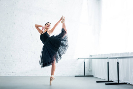 全长视图美丽优雅的年轻芭蕾舞演员在画室里练习芭蕾