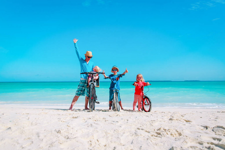 快乐家庭父亲与儿子和女儿骑自行车在海滩上
