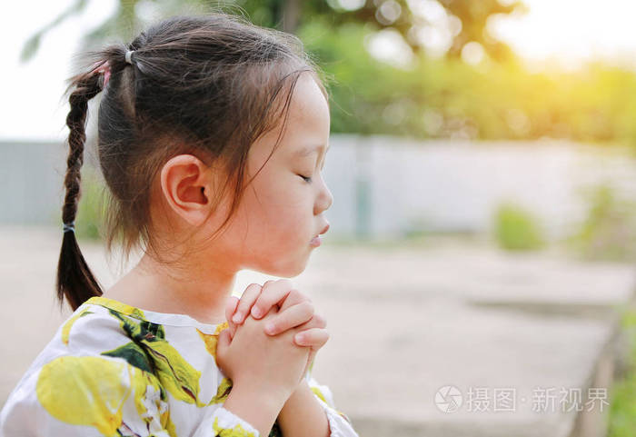 可爱的小女孩祈祷户外花园.灵性和宗教概念