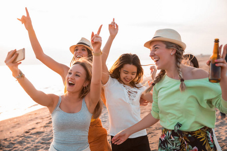 快乐的多种族年轻妇女在海滩上做一个自拍, 而他们在一个夏季聚会。朋友和假日概念