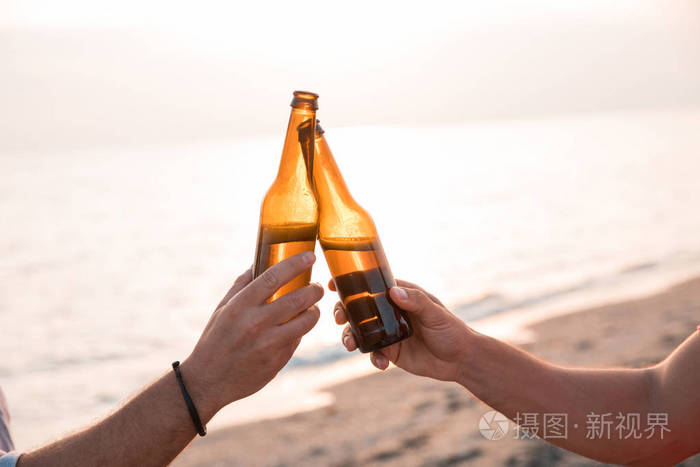 干杯!在海滩上 手里拿着瓶啤酒举杯祝酒.庆祝概念